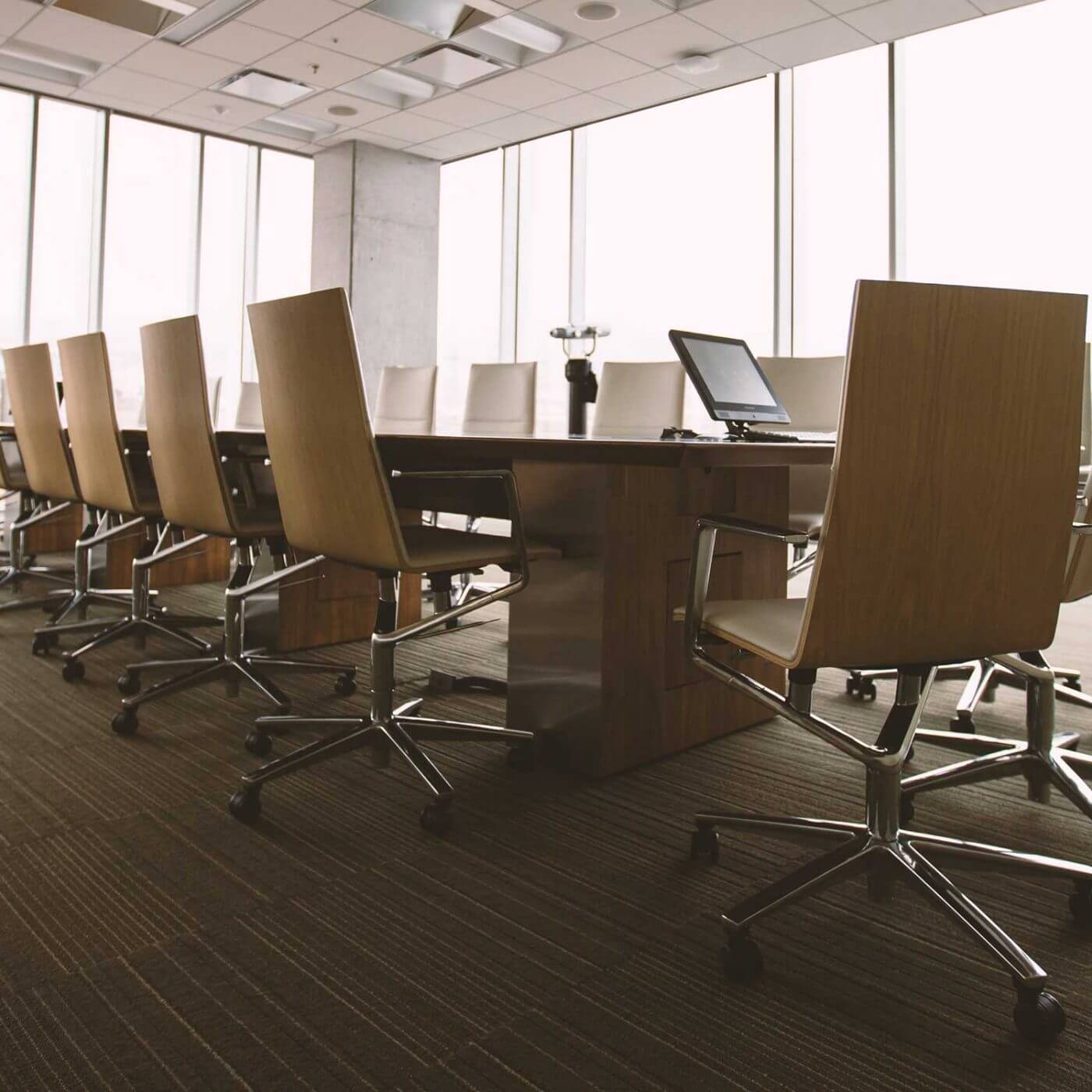 An empty conference room with a large table and many chairs surrounding it.